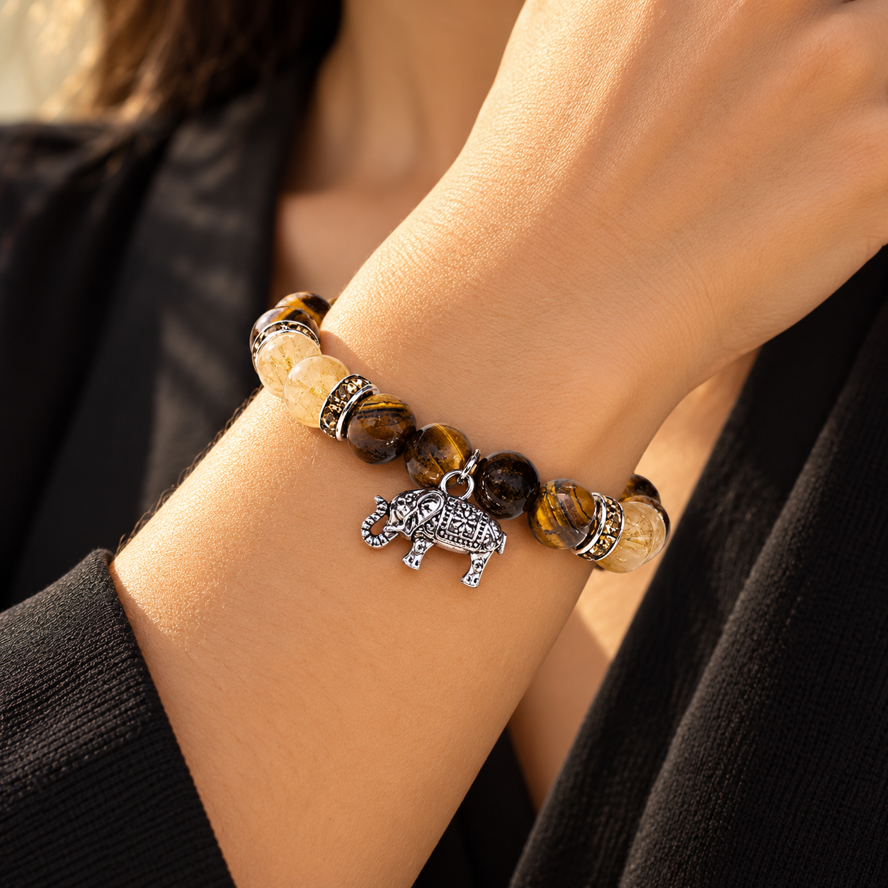 Pulsera de ojo de tigre y cuarzo rutilado con elefante llevada en la muñeca
